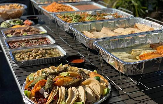 Full catering buffet line of grilled meats, tacos and sides